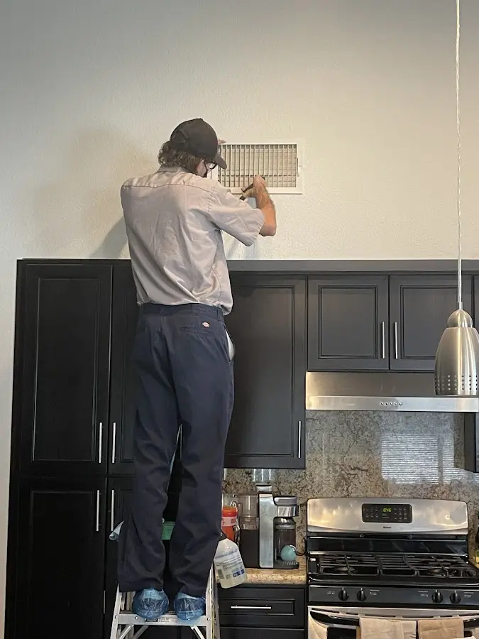 Technician inspecting an air vent during HVAC service in Geneva